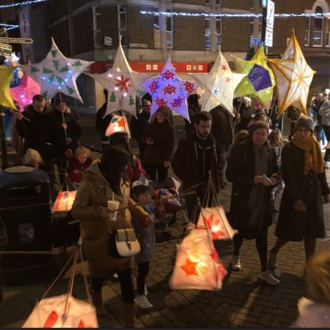 Crowds gathered around in a town centre holding custom made lanterns