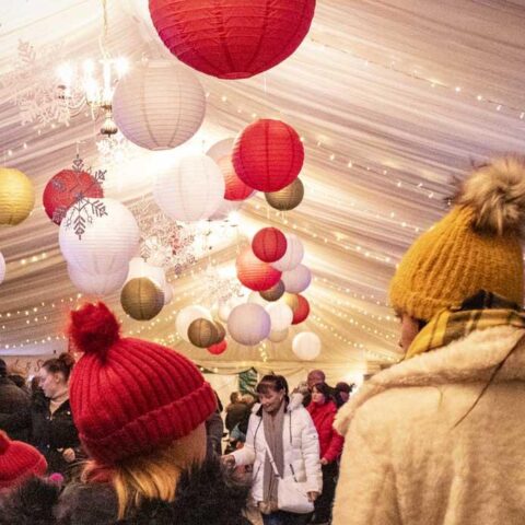 Woman and child walking under Christmas themed decorations in a marquee