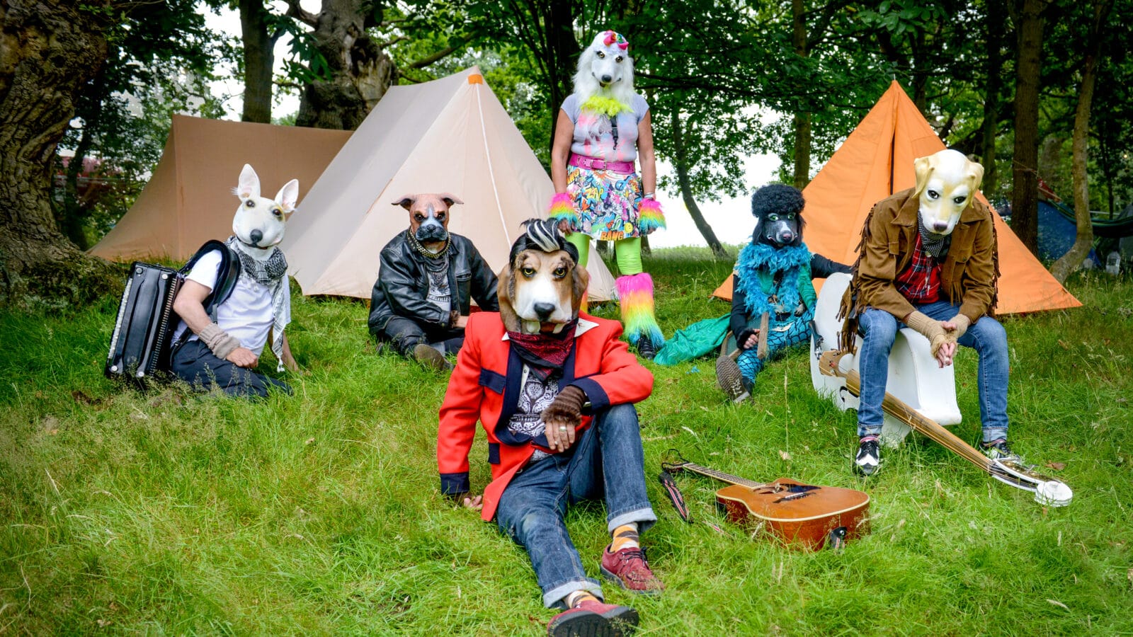 6 people lay on a lawn wearing dog masks surrounded by musical instruments