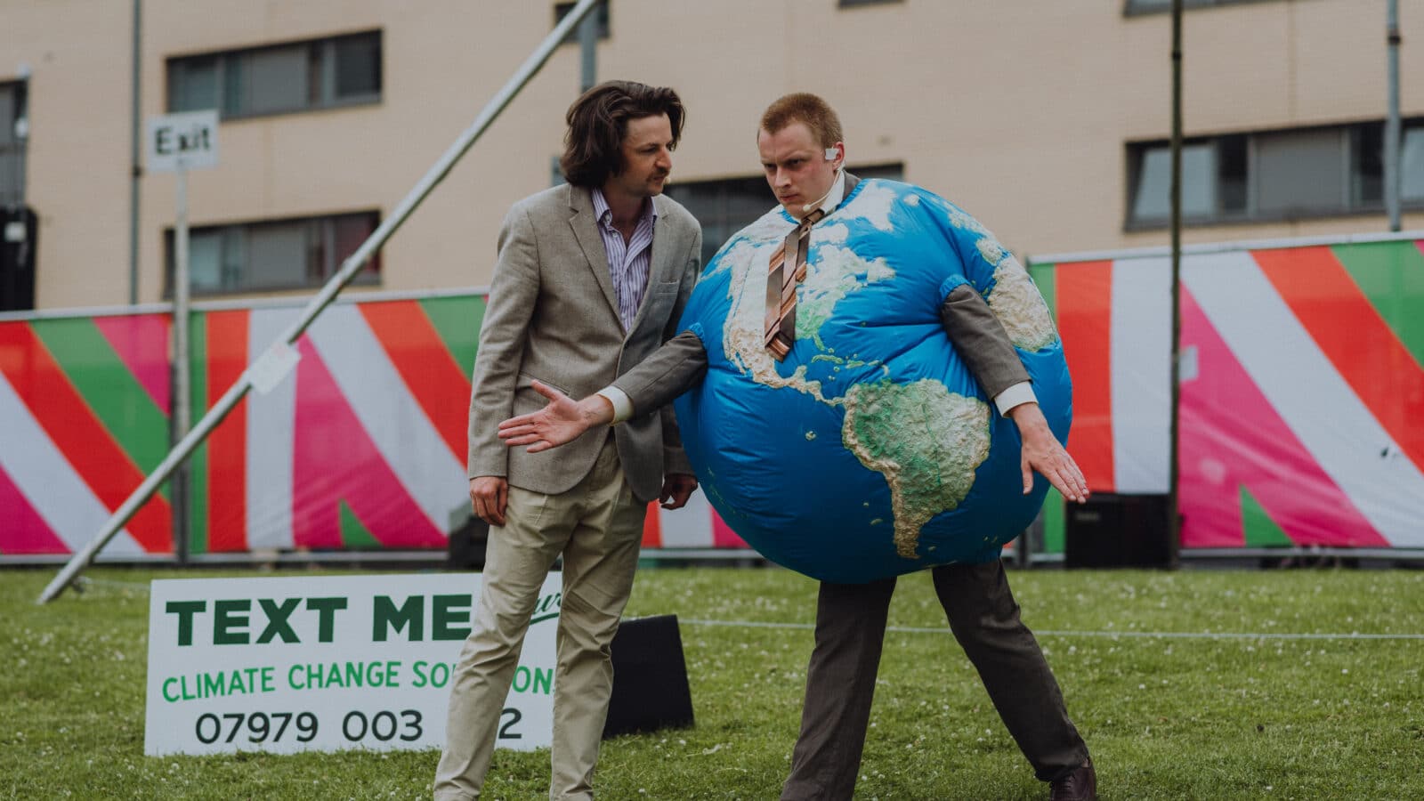 Two people on a field in conflict. one is dressed as the earth and the other as a business man
