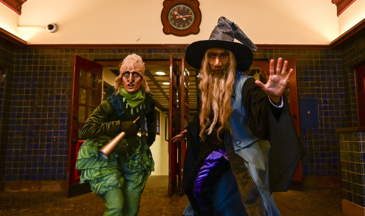 two people dressed as characters in front of large clock