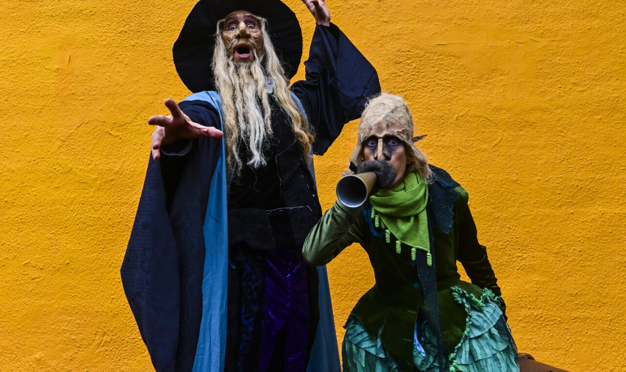 two people dressed as wizards posing in front of orange back drop