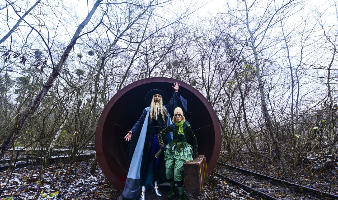 two people in costume posing in front of large pipe