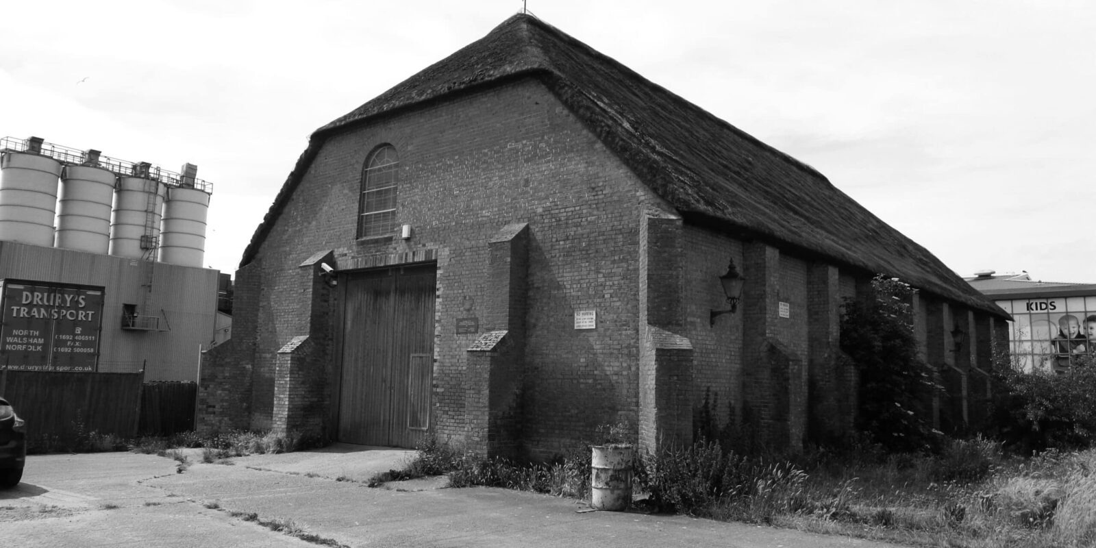 A black and white image of The Ice House in modern times. Situated in Great Yarmouth. A large oblong building with a thatched roof