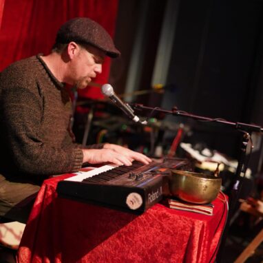 Man performing on keyboard singing into microphone at the Drill House