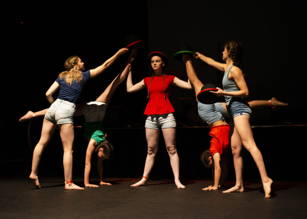 A group of children perfoming circus tricks in a dark room
