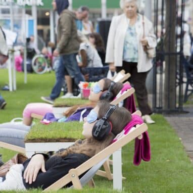 Crowds enjoying an immersive experience. Lounging in deck chairs wearing blindfolds.