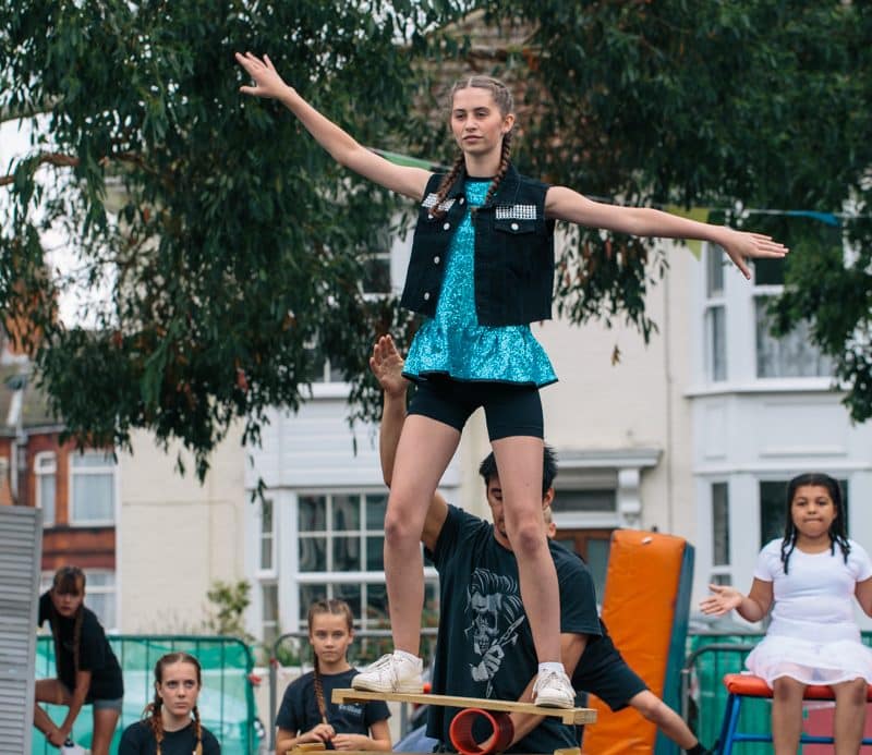 Girl balances on a rola bola on top of a barrel