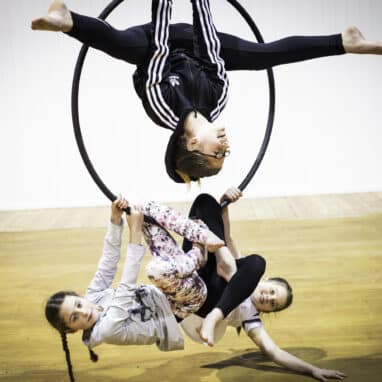 A group of children hang off a hoop in an acrobatic act