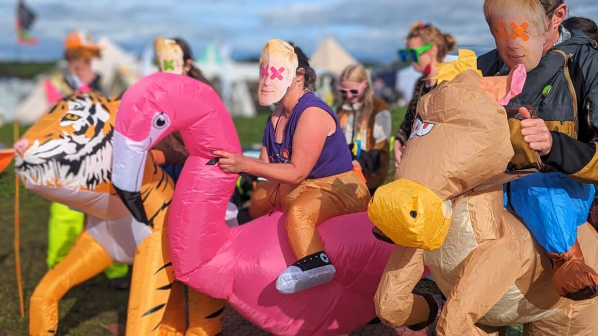 People dressed in politician masks riding inflatable animals in a race