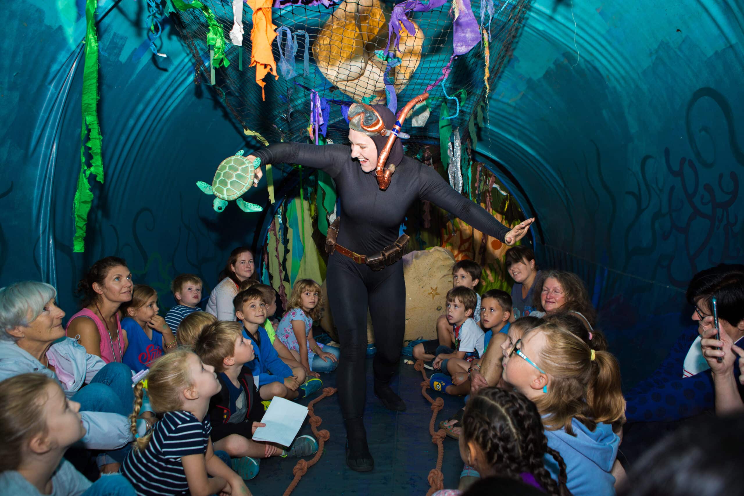 The Whale performance image. Scuba diver with a puppet entertains children.