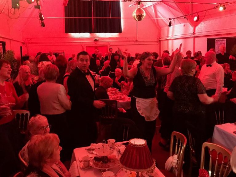 Posh Club attendees enjoying their evening. Room cast in a red light