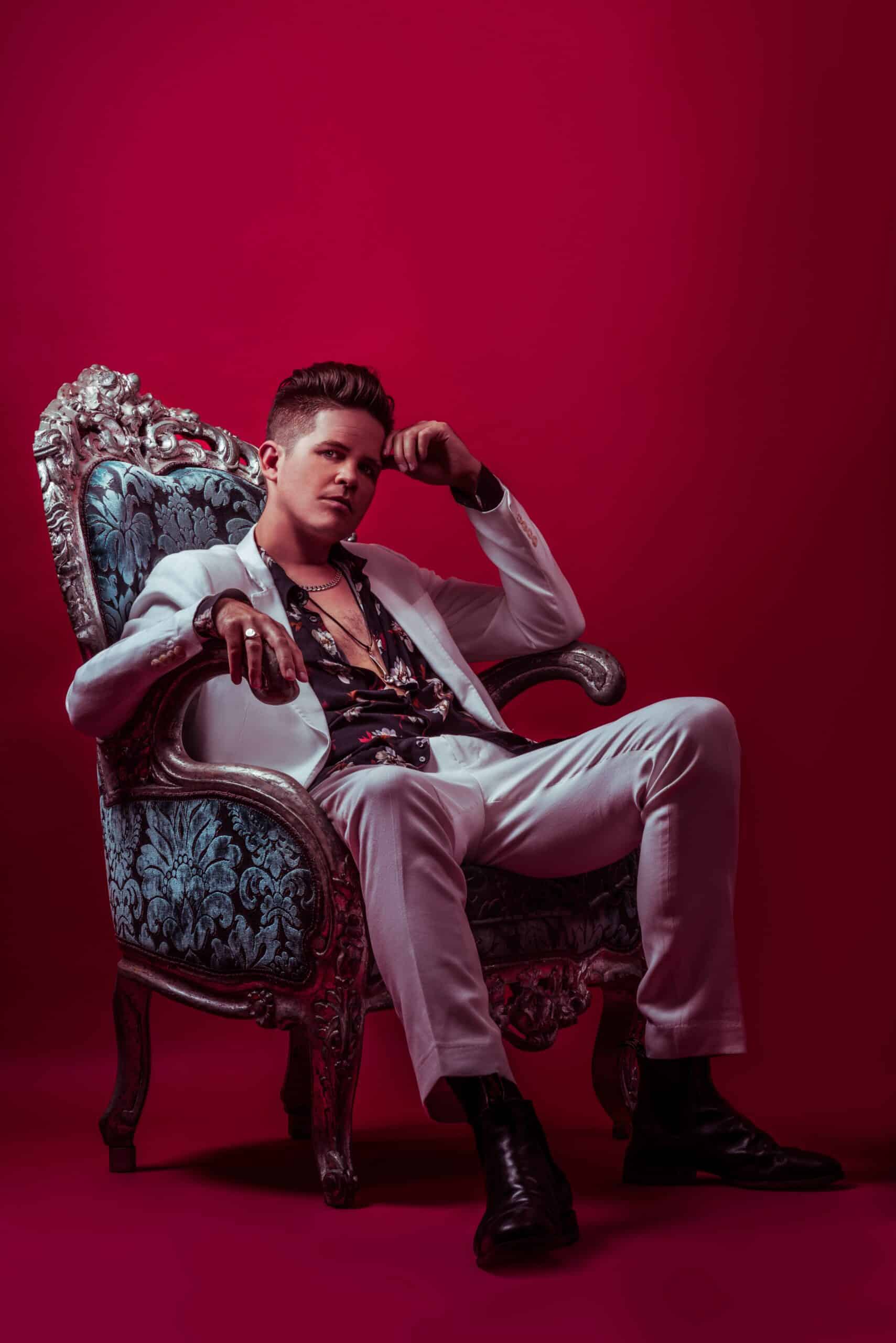 Photo of Luke Wright sitting on a chair in a red background