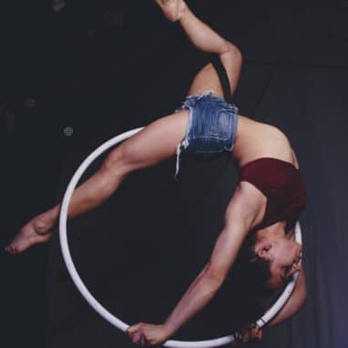 A female circus performer hangs upside down inside an aerial hoop