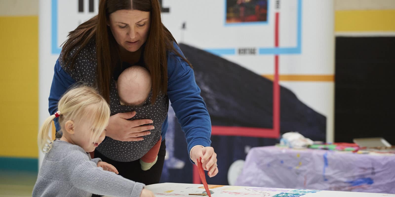 Mother and child getting involved painting and contributing to a creative workshop