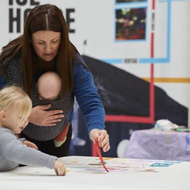 Mother and child getting involved painting and contributing to a creative workshop