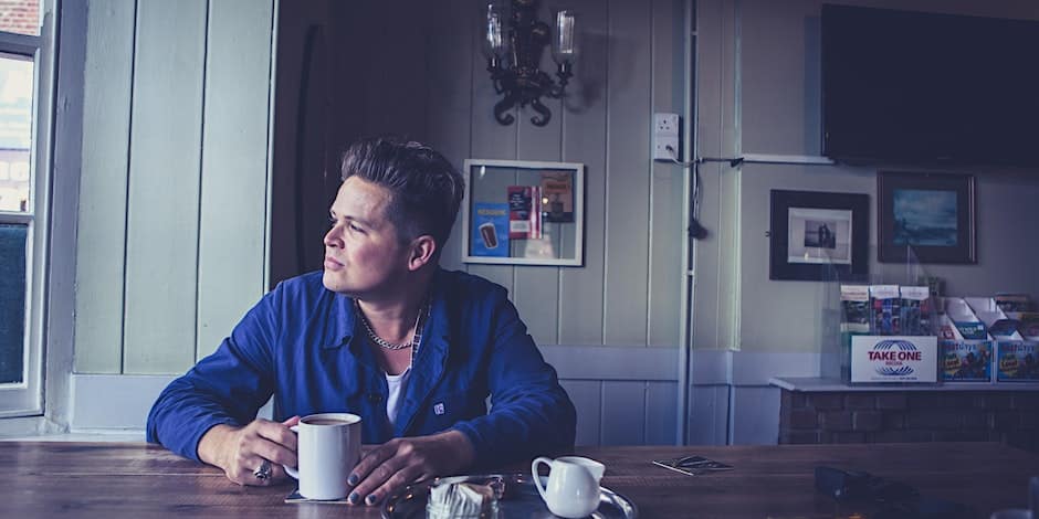 Promo photo of Luke Wright. Luke Wright with a cup of tea looking out of a window