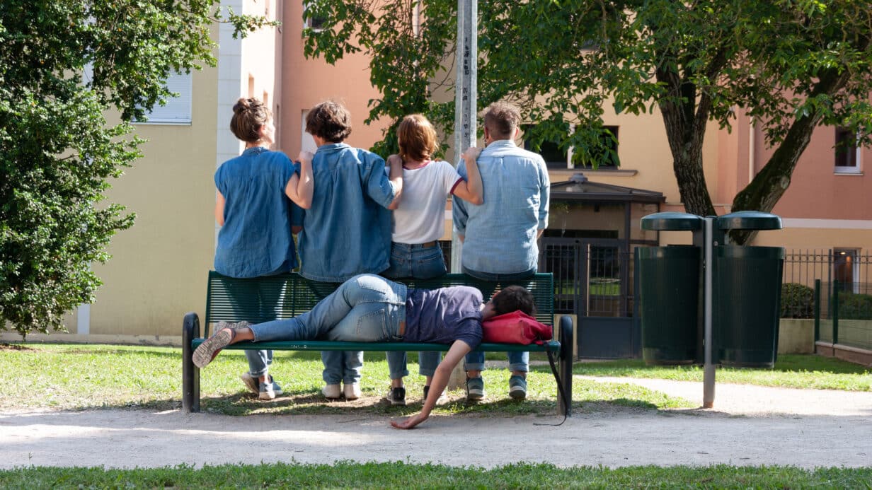 4 people with their back to the camera and one person lying on a bench