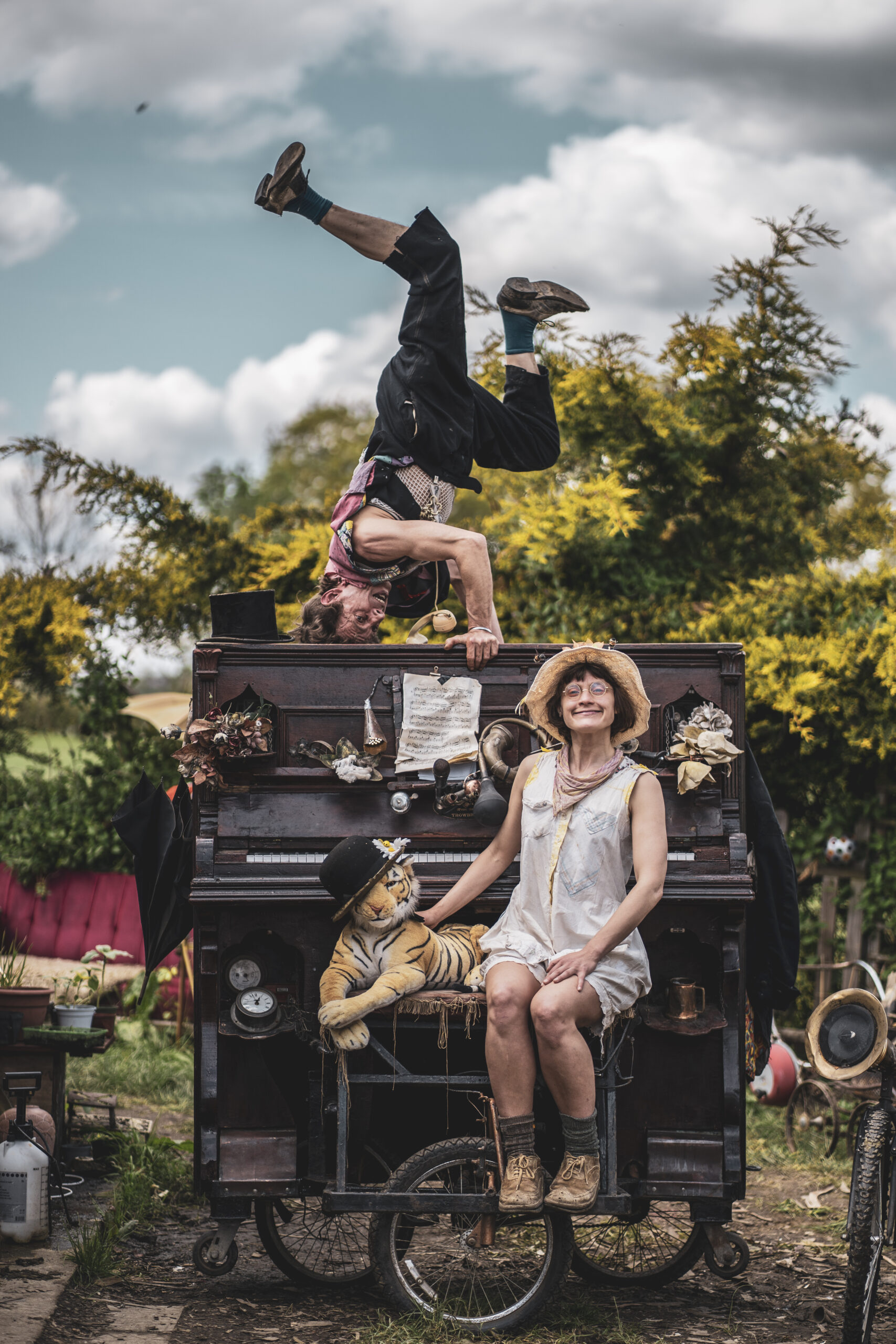 A man doing a head stand on top of a piano with a woman sat in front of it.