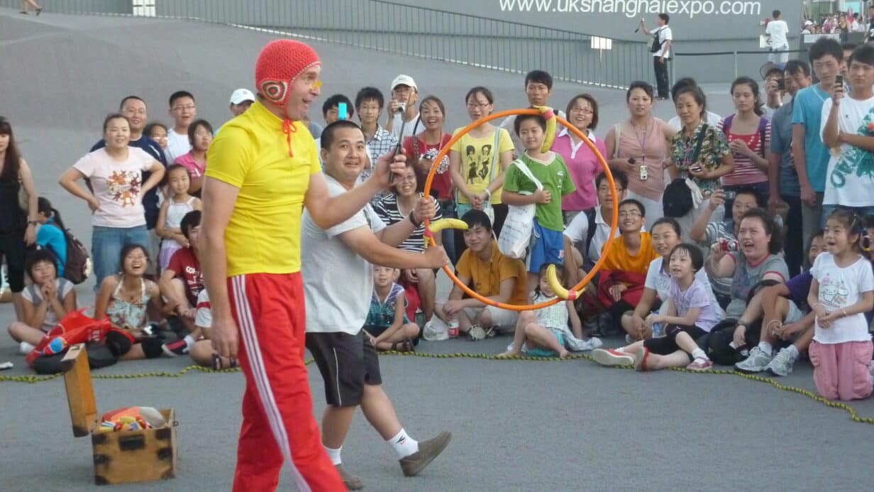 A man dressed in bright yellow and red and another man holding a hula hoop