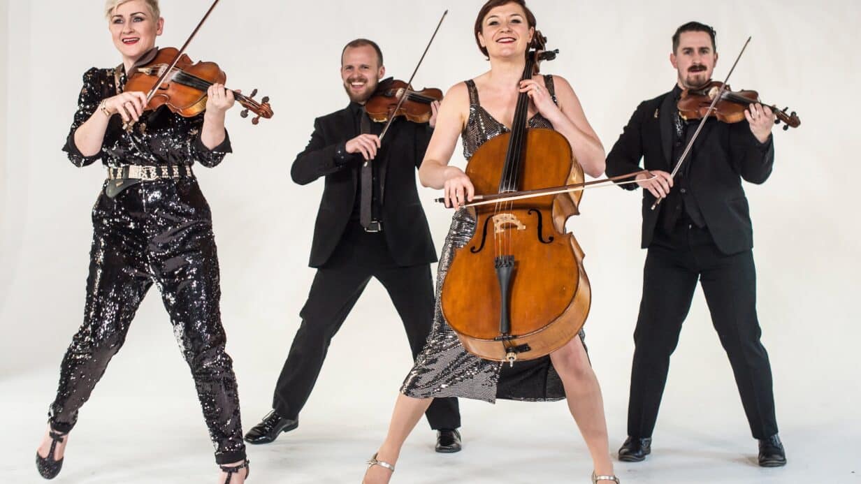 4 people dressed smartly holding violins