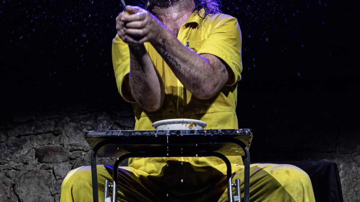 A person in a yellow jumpsuit holding a spoon with lots of powder in the air