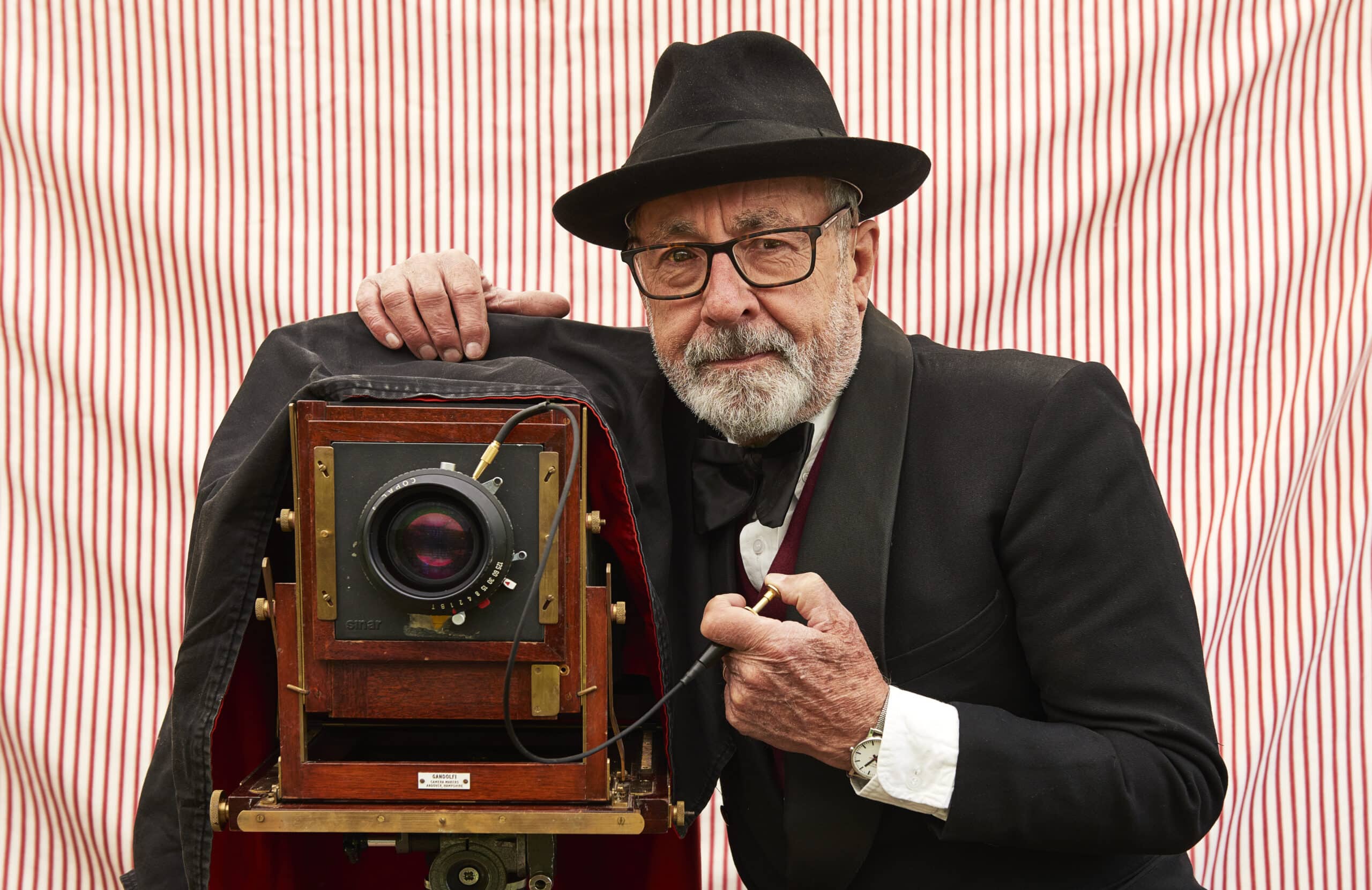 An old man poses with an old fashioned camera