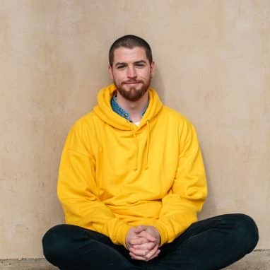 A man with a shaved head in yellow hoodie