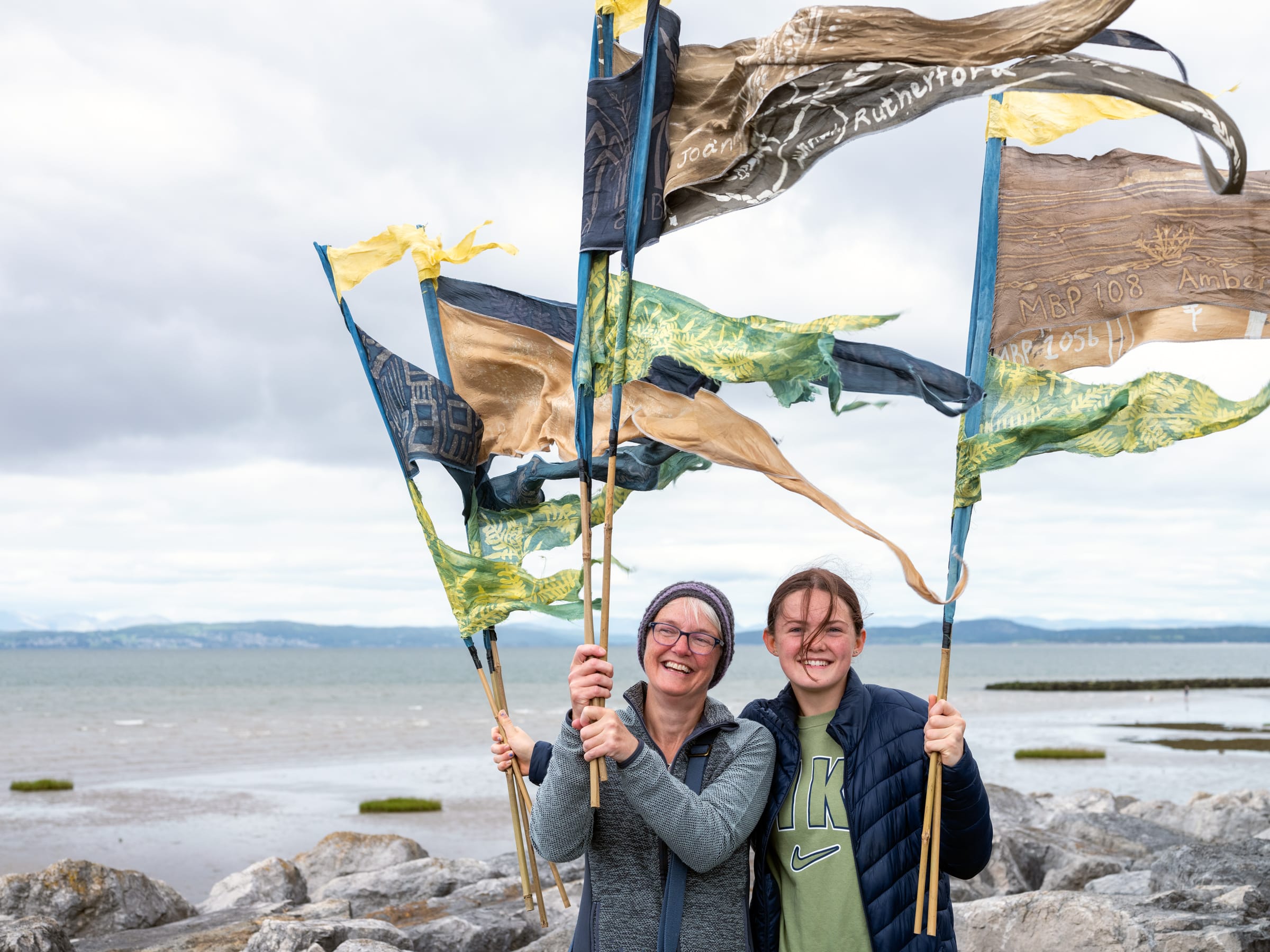 Two people holding naturally dyed flags