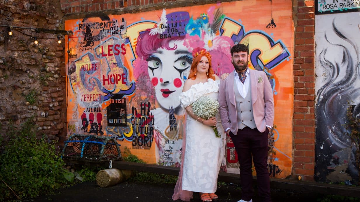 Bride and groom in front of graffiti wall