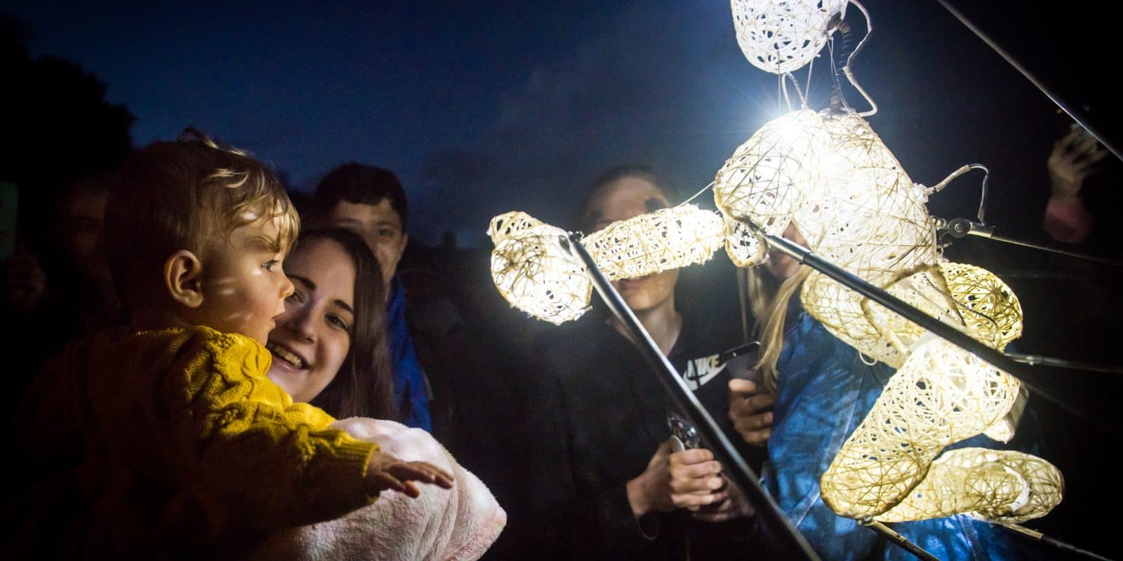 Out There Festival image. An illuminated puppet speaking to a child