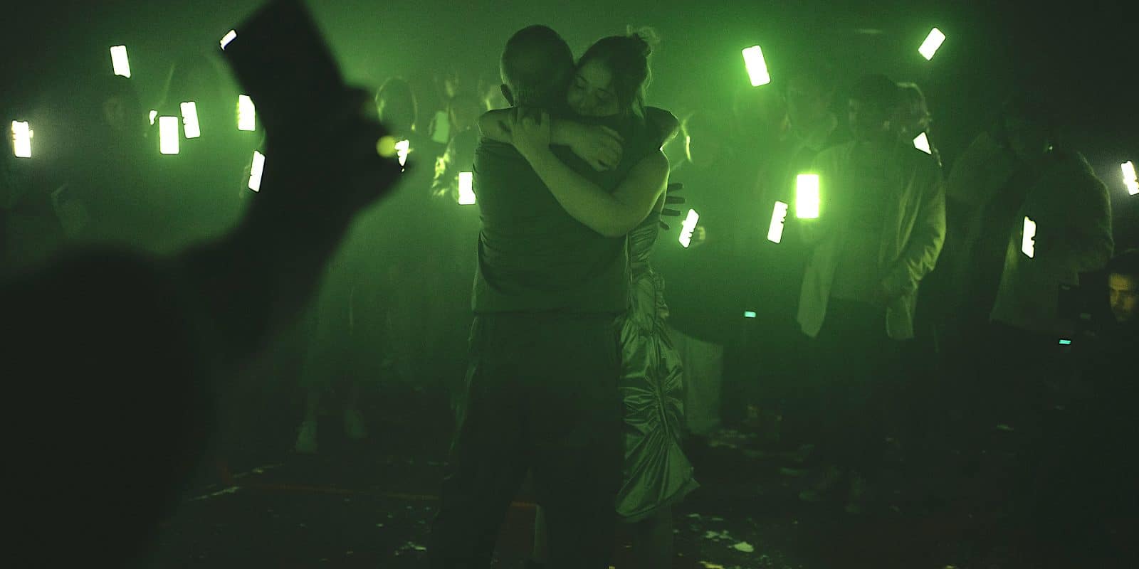 1 Odissees_© LUCAROCCHI_2023_73 – La Mecànica Audience hold their phones screens up to a man and woman hugging
