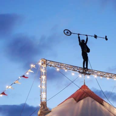 Man holds a unicycle on top of a big top tent