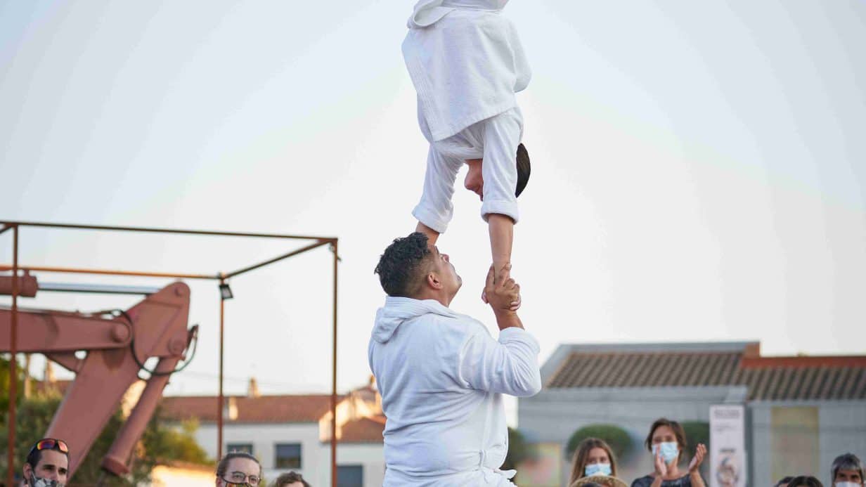 Man on bike balancing person upside down on his hands