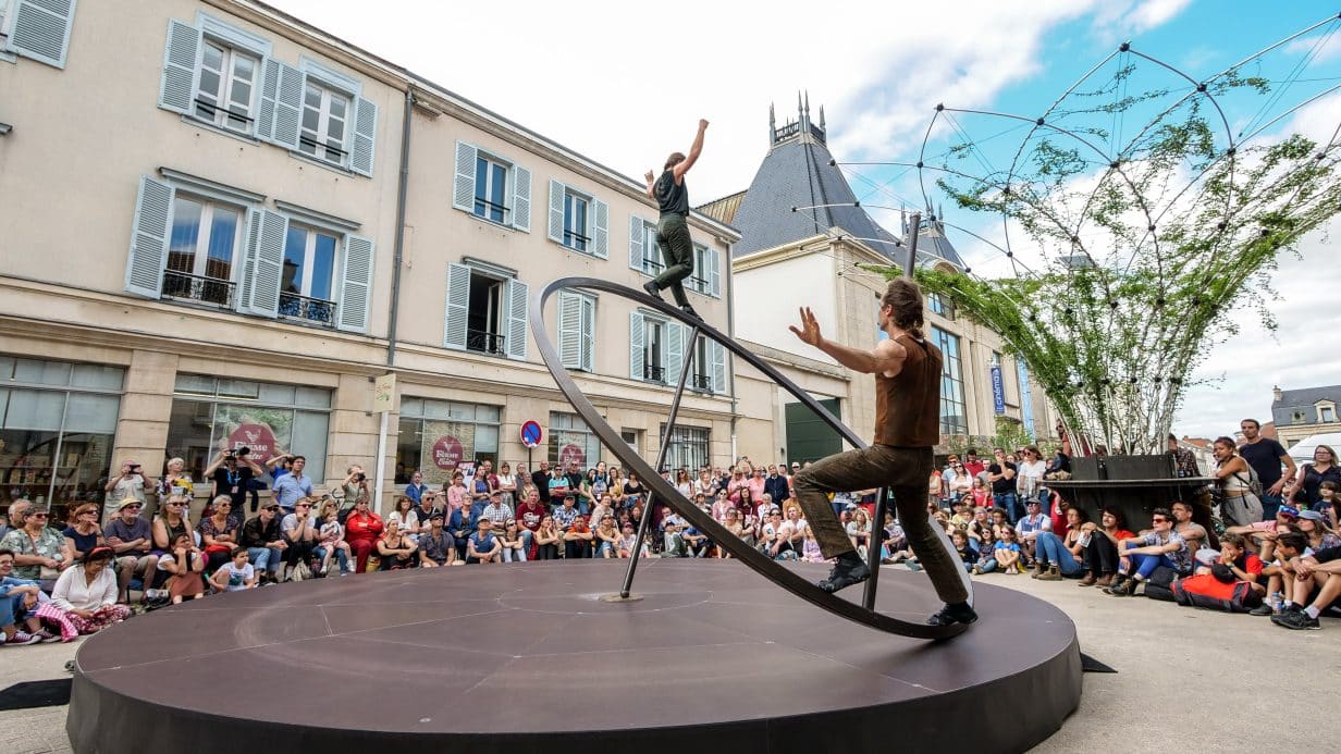 Circus performers balancing on a giant spinning top.