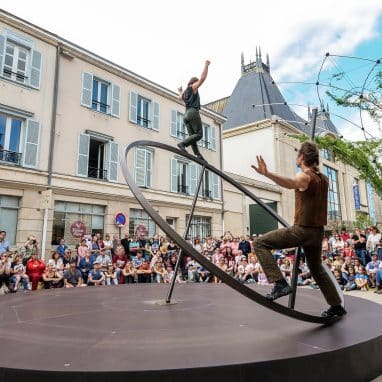 Circus performers balancing on a giant spinning top.