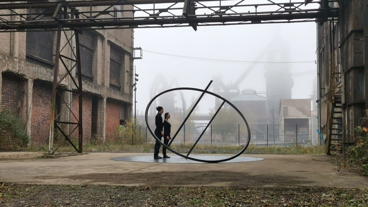 Two people balancing with a giant spinning top