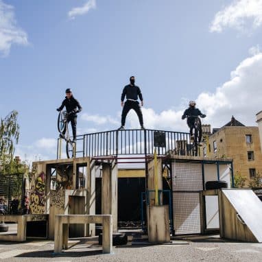 People dressed in black with bikes on top of a structure