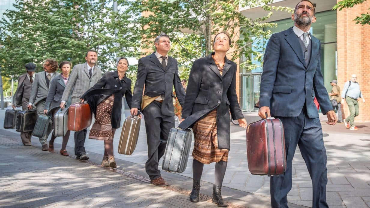 People dressed in suits in a line carrying suitcases