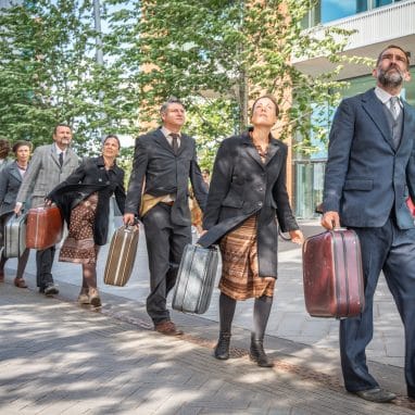 People dressed in suits in a line carrying suitcases