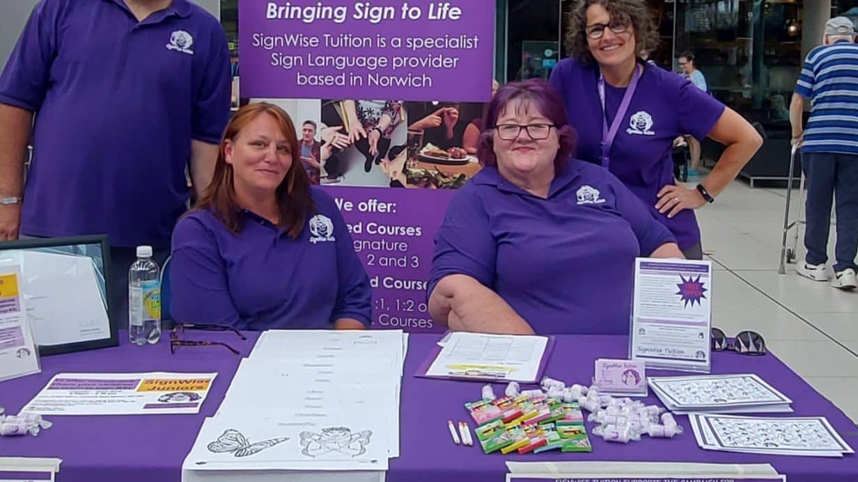 People sat around a stall wearing purple