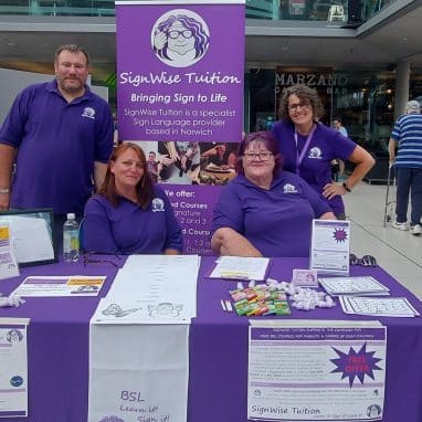 People sat around a stall wearing purple