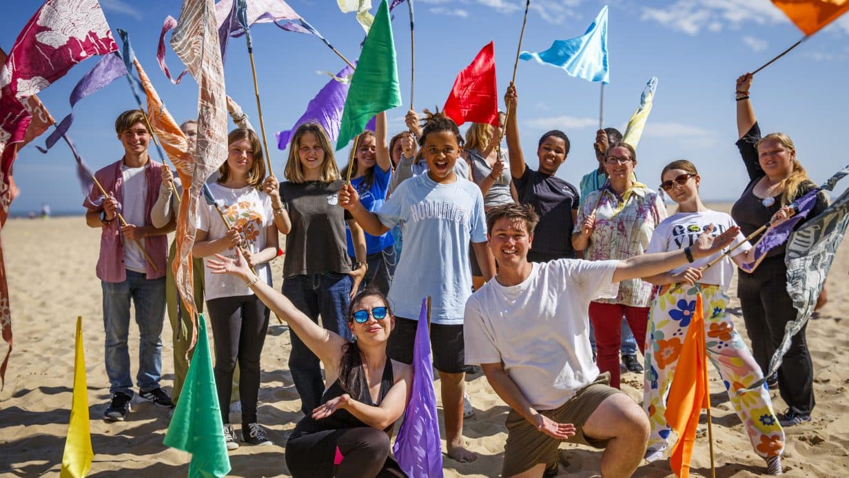 Group of young people smiling and holding flags