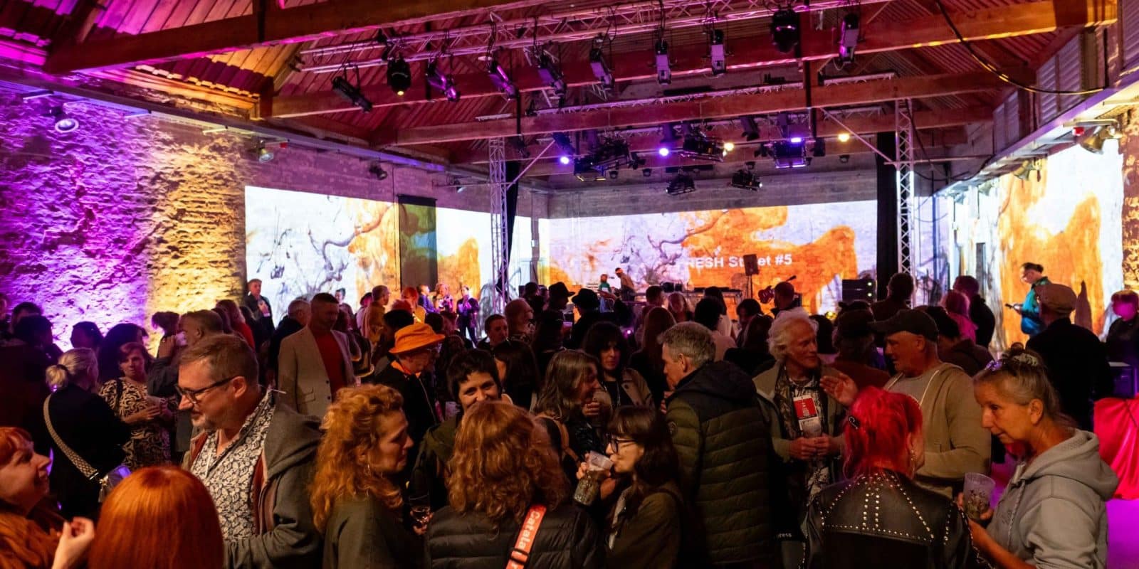 Shot of inside The Ice House. Lots of people surrounded by immersive and creative projections