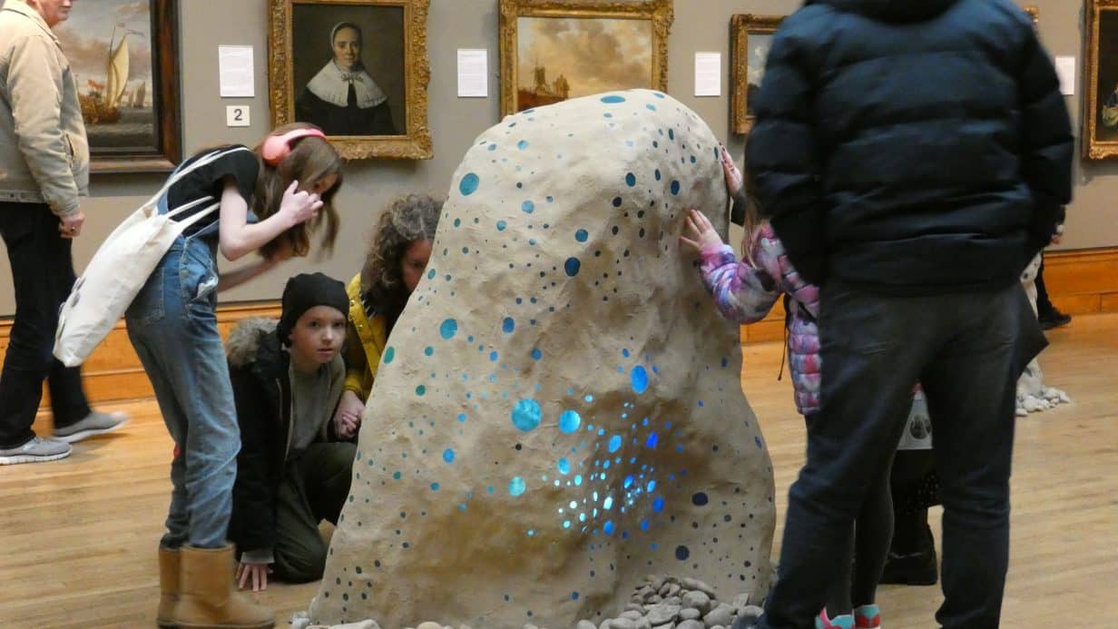 People in a musuem touching a sculpture