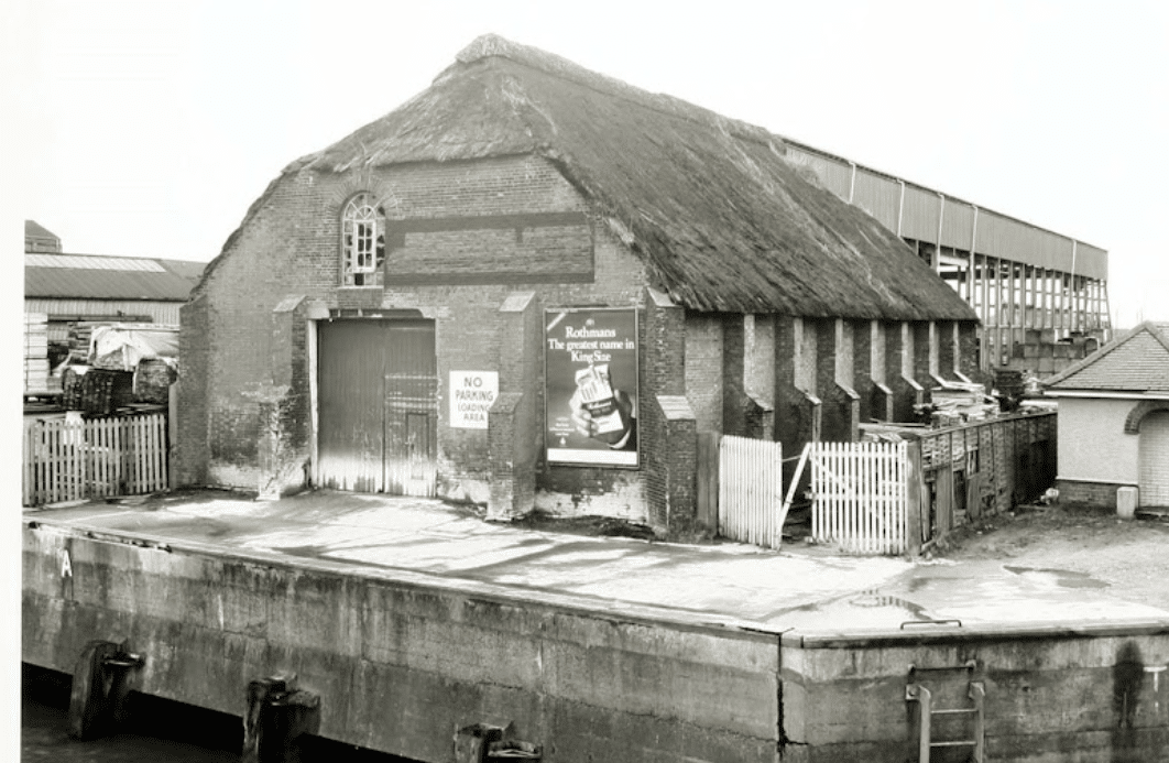 Black and white photo of ice house with thatched roof