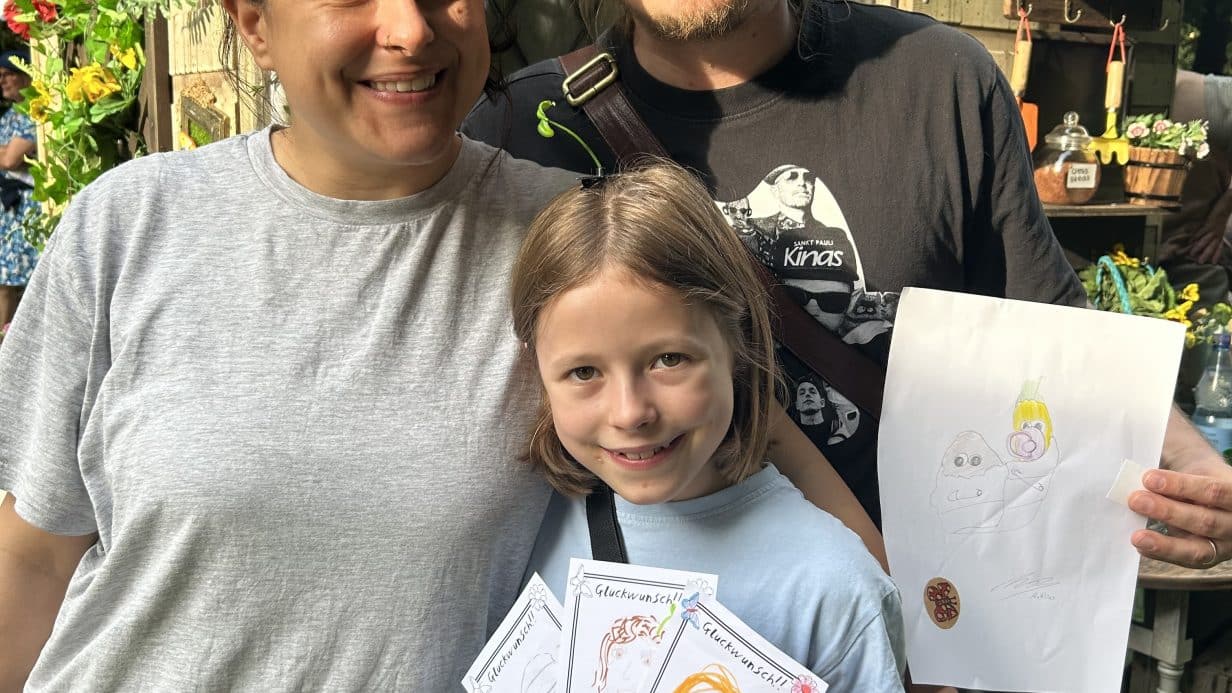 Family posing with their artwork outside The Magic Shed